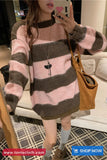 Person wearing a pink and brown striped sweater with a handbag, taking a mirror selfie.