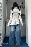 Person wearing a polka dot hoodie and blue jeans in a bedroom setting.