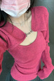 Person wearing a pink sweater with a cut-out design, standing on a gray floor.