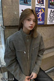 Person wearing a gray jacket sitting against a wall with posters.