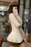 Person taking a mirror selfie wearing a beige lace dress and brown cap in a casual setting.