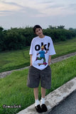 Person wearing a white t-shirt with a graphic design outdoors