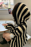 Person wearing a black and beige striped hoodie sitting at a table.
