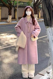 Person wearing a pink coat and white pants on a street.