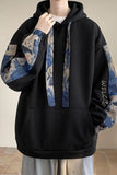 Black hoodie with artistic sleeves and text on a neutral background