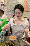 Woman eating at a restaurant with a colorful menu in the background