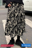 Person wearing a black and white patterned skirt on a street.