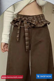 Brown wide-leg pants with a plaid belt and beige jacket, brand 'TomsCloth' visible.