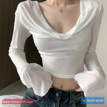 Person wearing a white long-sleeve crop top and blue jeans with a visible brand logo.