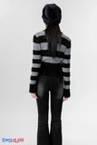 Person wearing a black and gray striped sweater and black pants on a white background