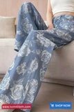 Person wearing blue floral pants sitting on a couch with 'TomsCloth.com' branding.