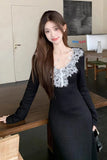 Woman in a black dress with lace details standing in an office setting.