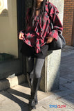 Person wearing a red plaid shirt, black pants, and knee-high boots leaning against a wall.