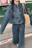 Person wearing a denim outfit with a straw bag on a street.