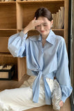 Woman wearing a light blue shirt with a wooden bookshelf in the background