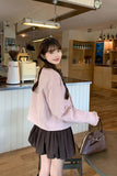 Woman in a pink sweater and black skirt standing in a modern kitchen.