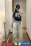 Person wearing a navy blue sports jersey with white lettering and light gray cargo pants, standing in a room.