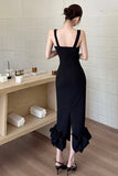 Woman in a black dress standing in a room with a wooden shelf and white wall.