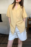 Person wearing a yellow oversized shirt and light blue shorts indoors.