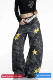 Person wearing black camouflage pants with yellow stars and a black top on a white background.