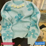 Light blue sweater with floral patterns on a blurred background