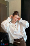 Woman wearing a white blouse with ruffled details in an indoor setting