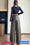 Person wearing a black long-sleeve top and wide-leg pants in an indoor setting.