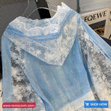 Blue lace fabric with white floral patterns on a hanger against a blurred background.