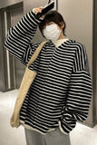 Person wearing a black and white striped sweater with a beige bag indoors.