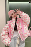 Person wearing a floral jacket with pink accents and a matching hat, posing in front of a mirror.