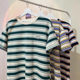 Striped t-shirts on hangers against a neutral background