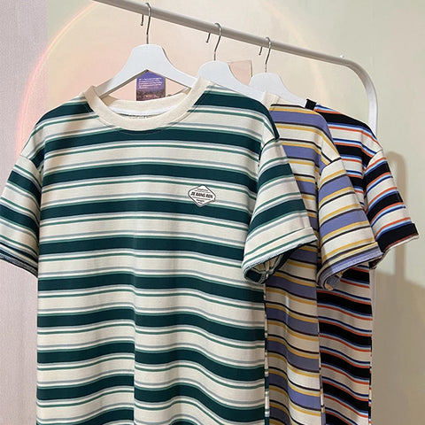 Striped t-shirts on hangers against a neutral background