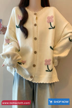 White cardigan with floral patterns worn by a person, with 'www.tomscloth.com' branding.