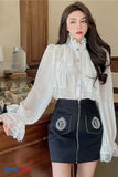 Woman wearing a white lace blouse and black skirt with a brand logo in a room setting.