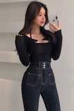 Person wearing a black long-sleeve top and dark jeans, taking a mirror selfie.