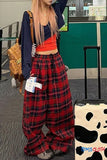 Person wearing red plaid pants with a cow print suitcase in an airport setting