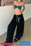 Person wearing a blue top and black wide-leg pants with a white wall and 'LILIPOT' branding in the background.
