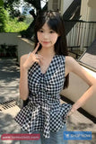 Woman in a checkered dress posing outdoors with a car in the background