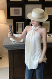 Woman taking a selfie wearing a white halter top and blue jeans indoors.