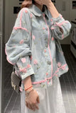 Person wearing a light blue floral embroidered jacket in an indoor setting