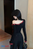 Woman wearing a black outfit with red plaid accents, standing indoors.