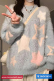 Person wearing a gray fuzzy sweater with star patterns, making a peace sign.