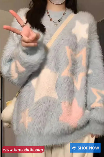 Person wearing a gray fuzzy sweater with star patterns, making a peace sign.