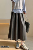Person wearing a gray skirt with a plain background