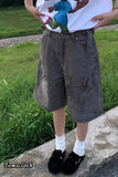 Person wearing a white t-shirt with a colorful design and brown cargo shorts standing on grass.