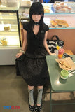 Woman in a black polka dot dress sitting at a table in a bakery.
