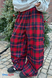 Red and blue plaid pants worn by a person standing next to a Christmas tree.