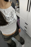 Person wearing a white tank top with a black graphic design in a room.