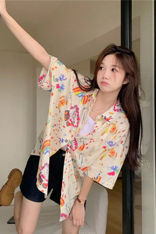 Woman wearing a colorful floral kimono-style shirt indoors.