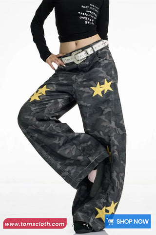 Black camouflage pants with yellow stars worn by a person on a white background